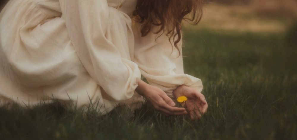 A woman cooling herself with a fan experiencing menopause hot.