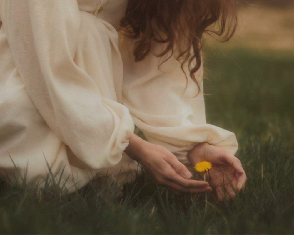 A woman cooling herself with a fan experiencing menopause hot.