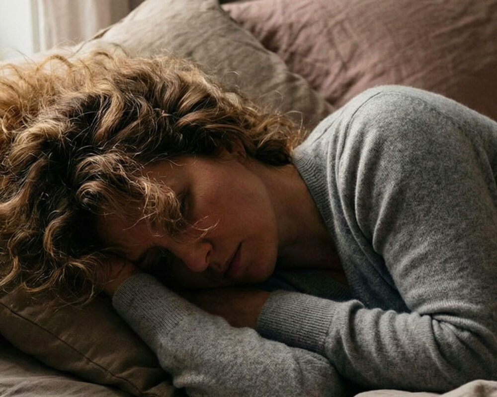 Woman resting in bed feeling fatigued despite normal blood test results, highlighting hidden hormonal and metabolic imbalances.